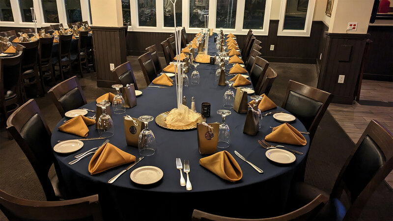 Long banquet dining table with blue table cloth and gold napkins